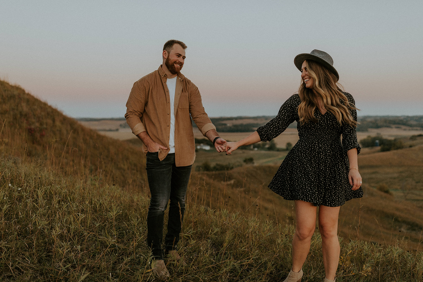 18 Top Spots For Your Destination Engagement Photos: Couple smiling at each other as they hold hands in the middle of a field in Montana.