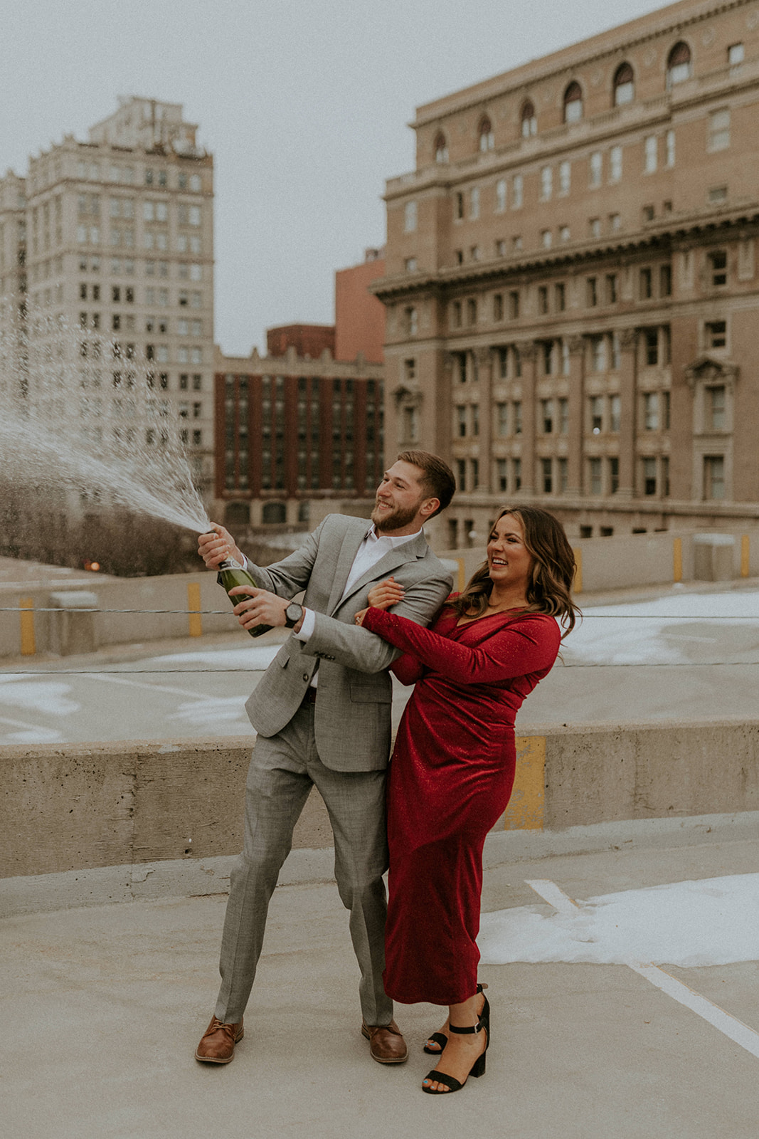 Couple people open a bottle of champagne together during their engagement session with photographer McKenna Christine