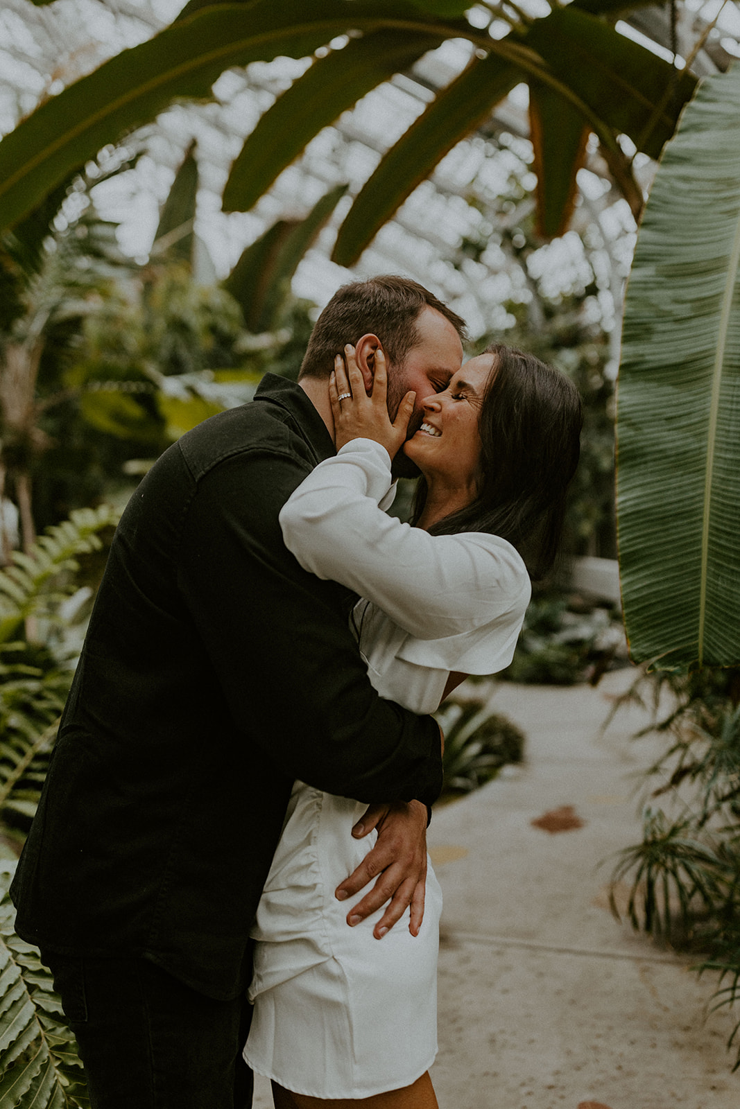 7 Engagement Photo Tips For The Perfect Engagement Session: Couple wrapping their arms around each other and smiling at a garden.
