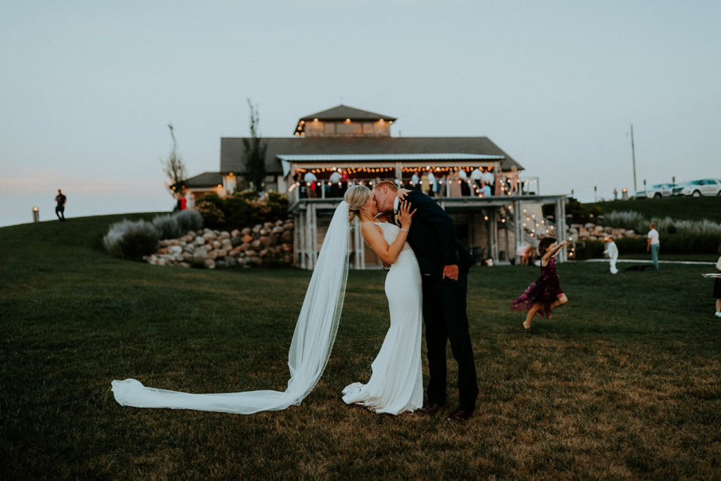 Bride and groom sharing a kiss in front of wedding venue at Glacial Till Vineyard