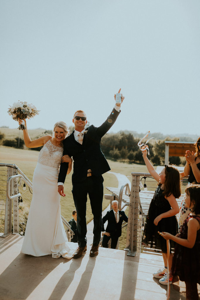 Newlywed couple raising their hands as guests cheer at their Glacial Till Vineyard outdoor reception