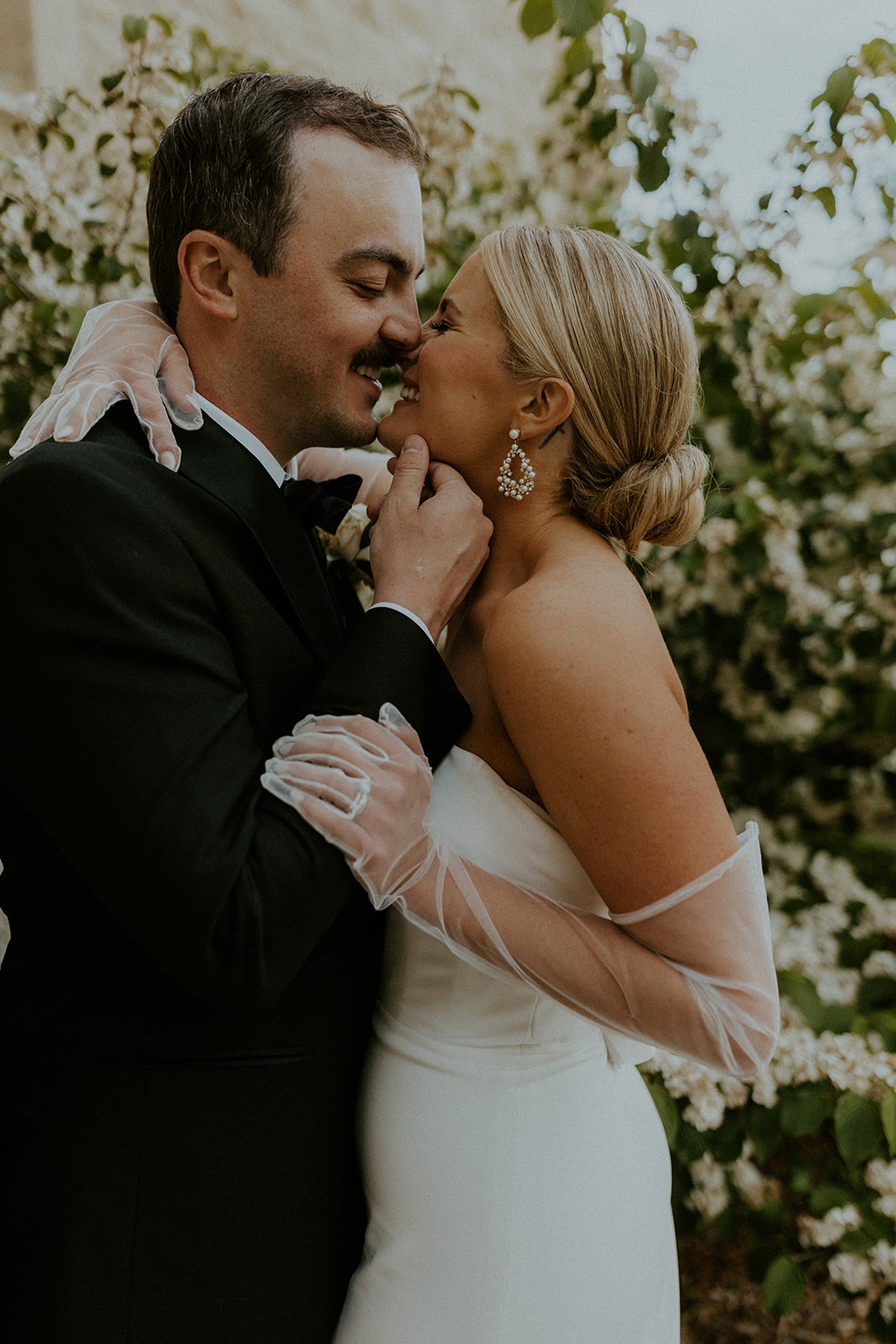 How to Choose A Wedding Photographer That's Perfect For You. Couple smiling as they lean in for a kiss.