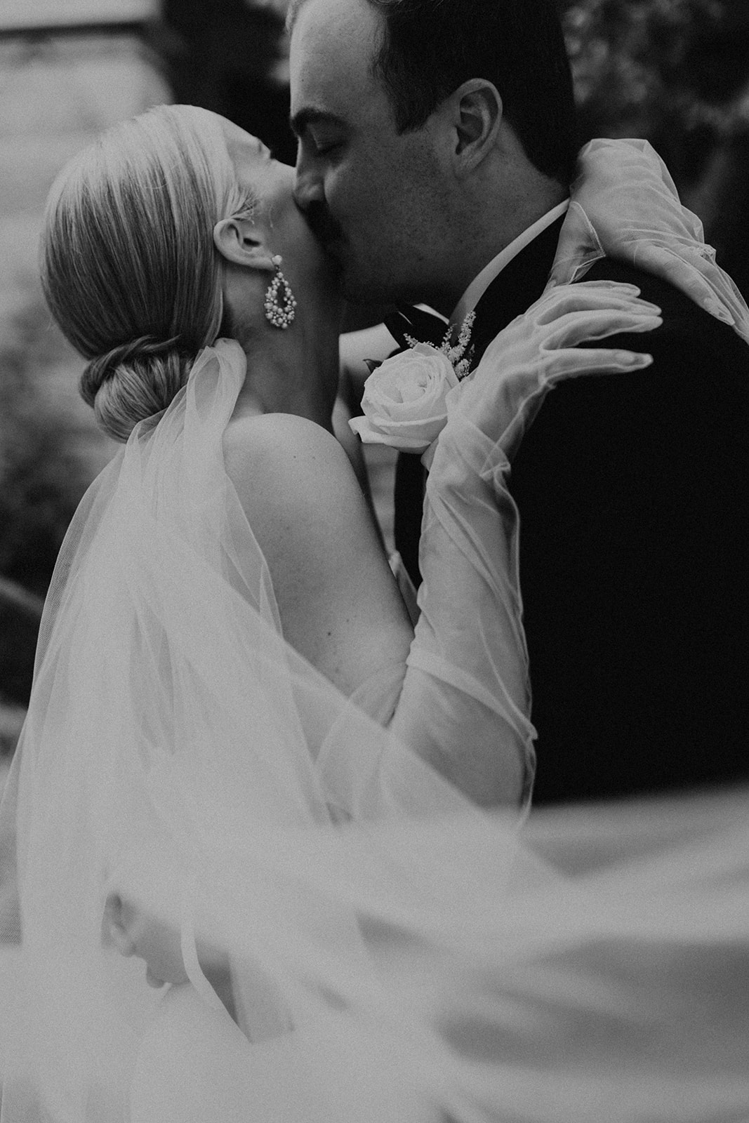 Black and white photo of groom planting kiss on bride's cheek, taken by McKenna Christine Photography