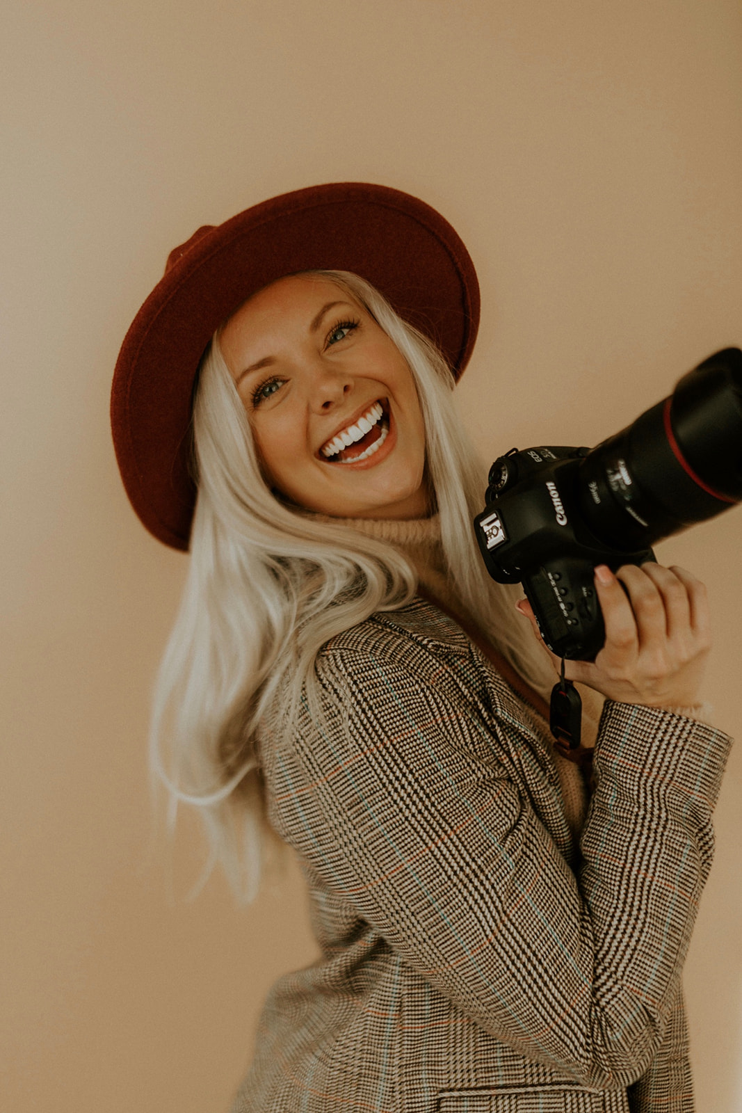 Travel photographer McKenna Christine smiling at the camera with her Canon camera in hand