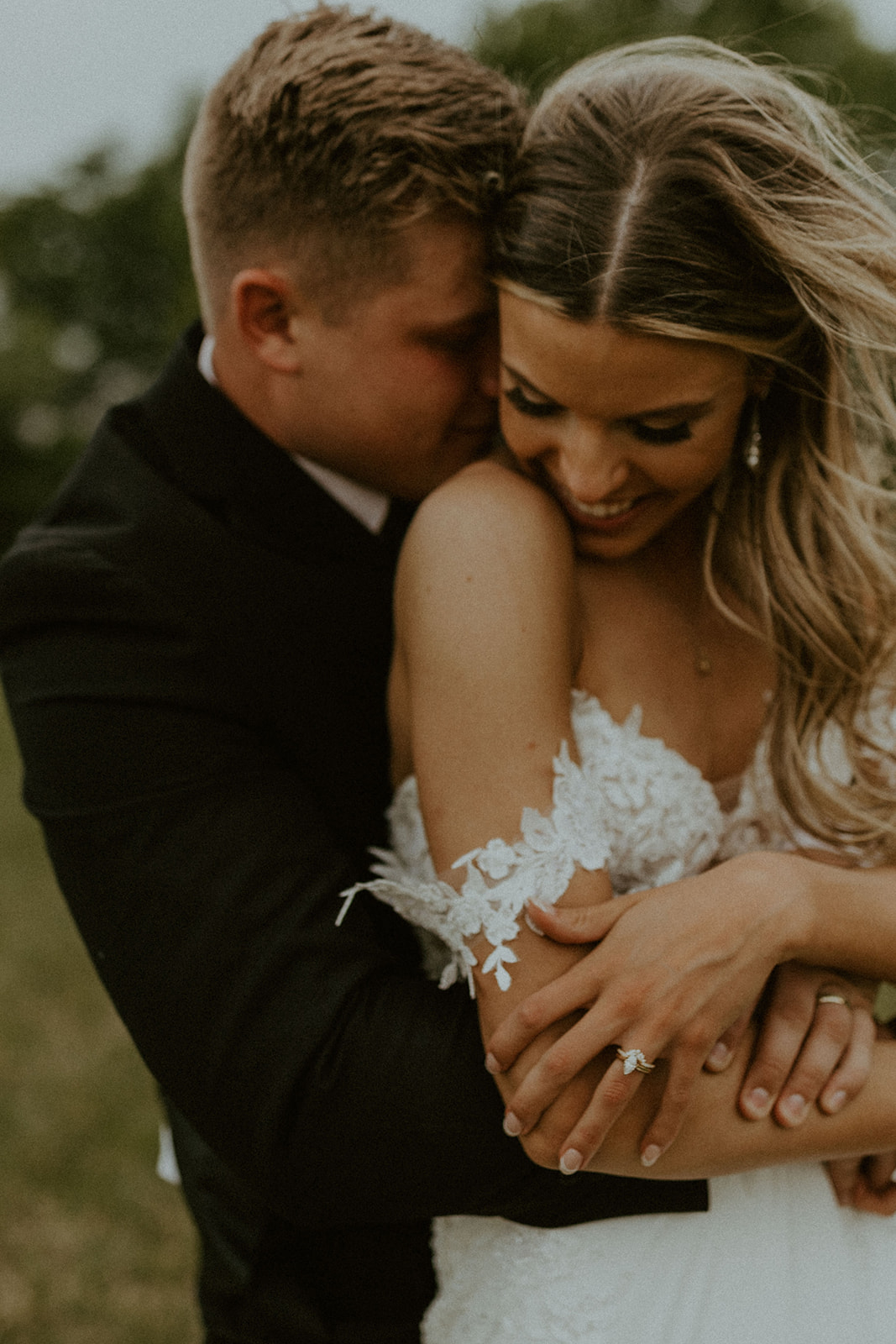 How to Choose A Wedding Photographer That's Perfect For You. Groom hugs bride from behind during wedding shoot.