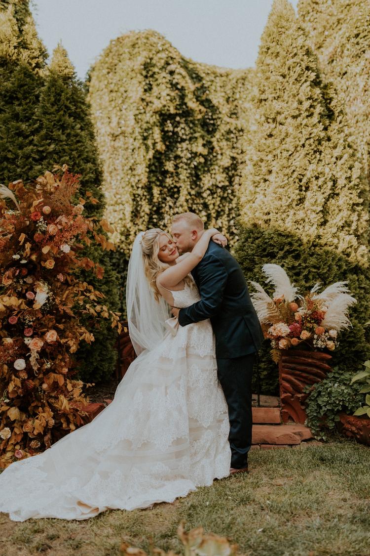 19 Non-Traditional Wedding Ideas To Make Your Wedding Day Uniquely Yours. Groom planting a kiss on bride's cheek as she wraps her arms around him.
