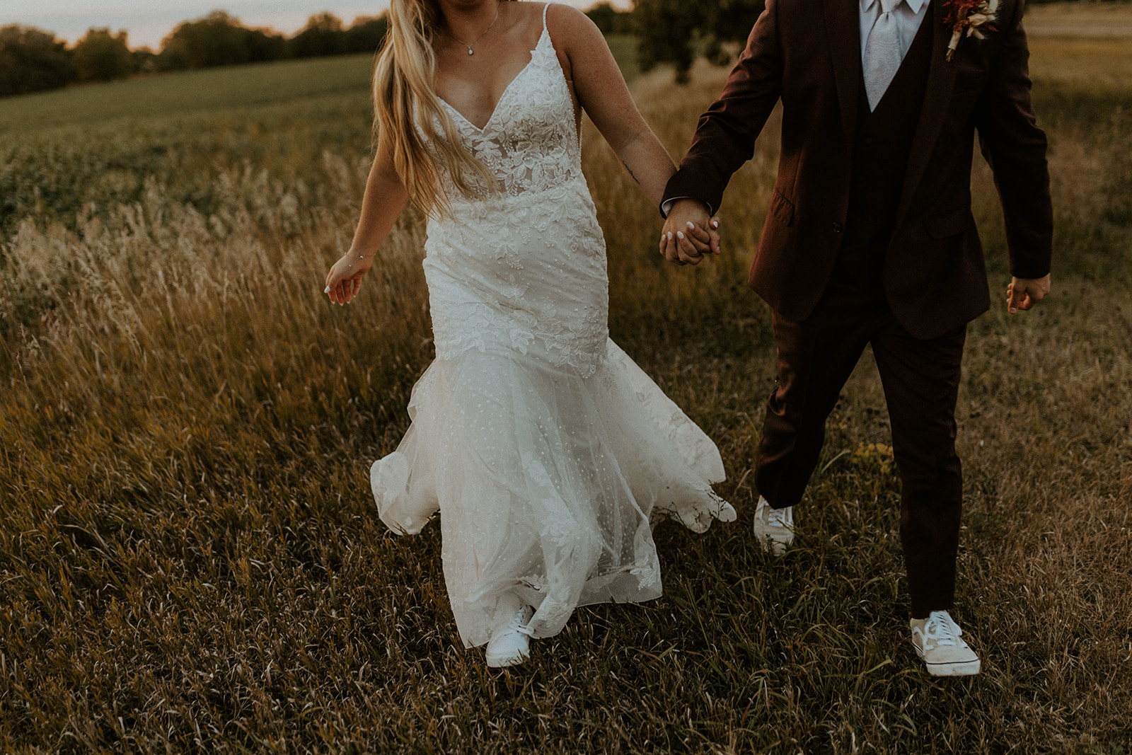 Top 5 Wedding Venues in Lincoln, NE (Including Pricing). Close-up shot of couple holding hands while walking through the grass.