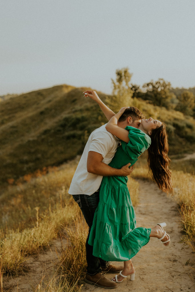 What to Wear For Engagement Photos + What NOT to Wear. Engaged couple sharing an embrace on the hill.