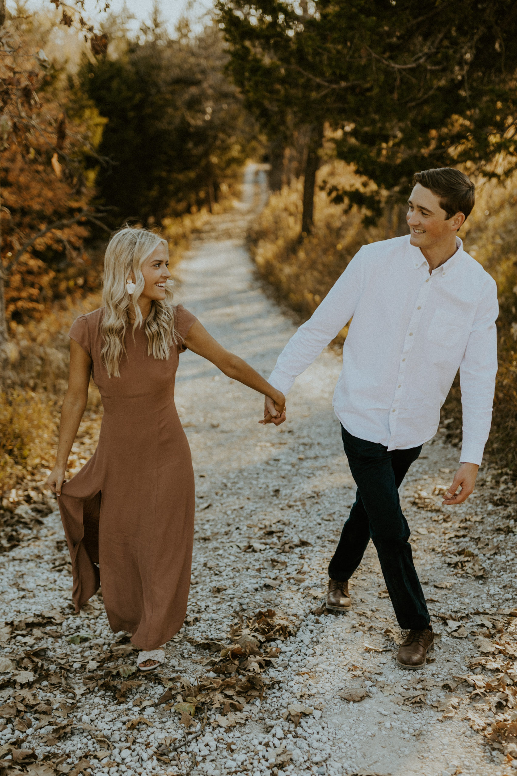 Engaged couple holding hands and smiling at each other during their engagement shoot with McKenna Christine Photography